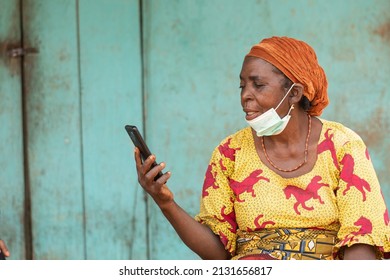 elderly african woman wearing face mask using her phone