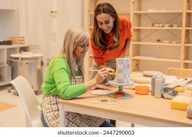 Elderly artist painting ceramics with guidance from a younger partner. - Powered by Shutterstock