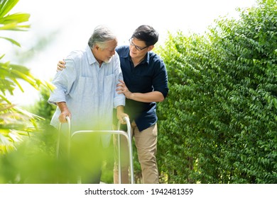 Elderly Asian Father And Adult Son Walking In Backyard. Positive Asian Man Caregiver Helping Patient