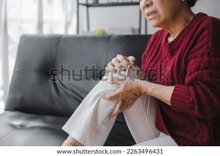 Elderly asian housewife woman sitting on sofa. knee pain