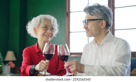 Elderly Asian Male And Female Couple Drinking Wine.