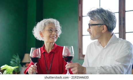 Elderly Asian Male And Female Couple Drinking Wine.