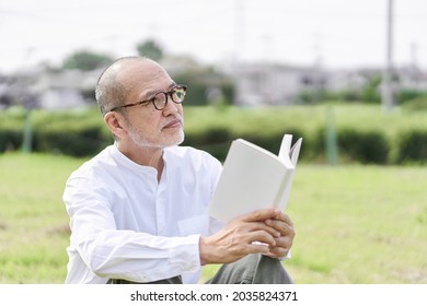 Elderly Asian Male Reading Outside