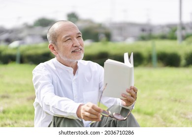 Elderly Asian Male Reading Outside