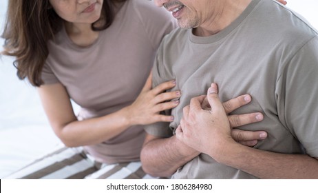 Elderly Asian man with chest pain from a heart attack, His wife was worried when she saw her husband sick, congenital disease, Heart disease, High blood pressure.