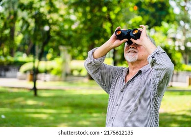 Elderly Asian Man Looking At Birds With Binoculars In The Park, Holiday Activities For Retired.