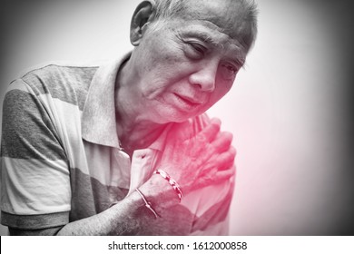 Elderly Asian Man Put His Hand On His Shoulder Because Of Shoulder Pain Or Muscle Pain. Black And White Tone With Red Spot On His Shoulder. Healthcare And Medical Concept.