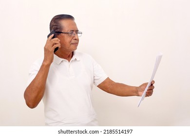 Elderly Asian Man Standing While Talking On The Phone And Holding Papers. Isolated On White.