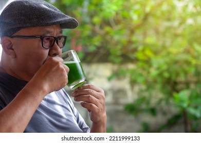 Elderly Asian Man Wearing A Cap And Drinking A Smoothie