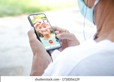 elderly Asian man wearing a mask Use a smartphone to chat with niece via video call. Concept social distance, virus infection prevention - Powered by Shutterstock