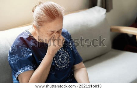 Elderly Asian woman crying wipes tears with hands feels unhappy, bad news.