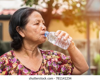 The Elderly Asian Woman Drinking Water From Bottle In Park