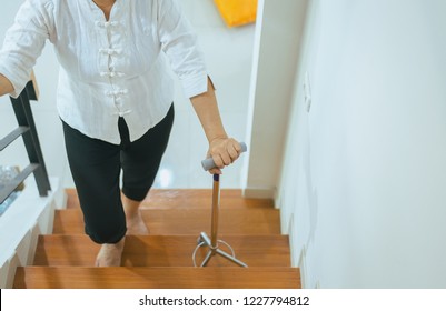 Elderly Asian Woman Holding Sticks While Walking Up Stair At Home