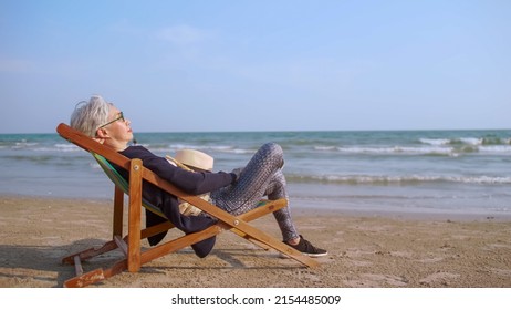 Elderly Asian woman relaxing on a peaceful beach. - Powered by Shutterstock