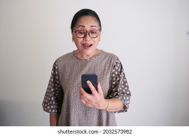 Elderly Asian Woman With Shocked Face Expression While Looking To Her Mobile Phone