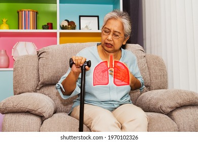 Elderly Asian Woman Suffers From Respiratory Pneumonia : Elderly Woman Sitting On A Sofa Is Unwell, Sick With Influenza, Has Symptoms Of Depression, Rapid Breathing And Chest Pain.