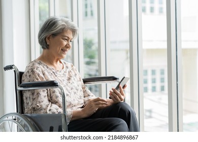 Elderly Asian Woman Using Mobile Phone On Wheelchair. Asian Senior Grandma Use Smart Phone While Sit On Wheelchair At Hospital