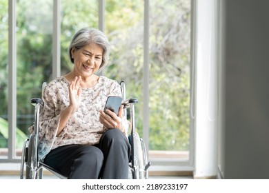 Elderly Asian Woman Using Mobile Phone On Wheelchair. Asian Senior Grandma Use Smart Phone While Sit On Wheelchair At Hospital