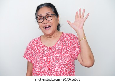 Elderly Asian woman waving her hand to greet someone