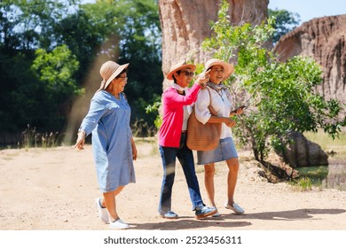 Elderly Asian women walking together in a natural park, smiling and pointing out interesting sights. Casual outfits, greenery around them emphasize joyful and relaxed outdoor experience. - Powered by Shutterstock