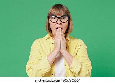 Elderly astonished surprised amazed shocked caucasian woman 50s wearing glasses yellow shirt cover mouth with hand isolated on plain green color background studio portrait People lifestyle concept. - Powered by Shutterstock