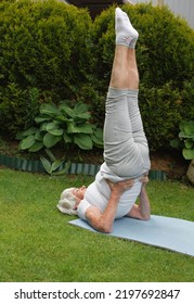 An Elderly Athletic Woman Does A Candlestick Exercise On The Grass In The Park.