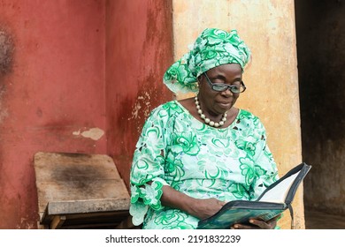 elderly attractive african woman casually dressed in traditional attire concentrating reading book - Powered by Shutterstock