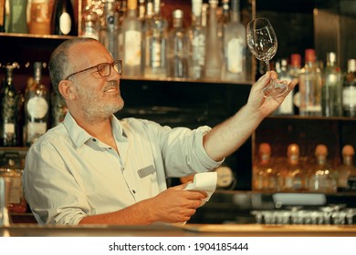 Elderly Bartender Cleans The Glass. The Concept Of Service