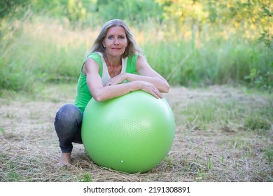 Elderly Beautiful Woman Is Doing Yoga With A Ball In Nature.