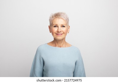 Elderly beautiful woman with a short pixie haircut in a blue sweater on a gray background - Shutterstock ID 2157724975
