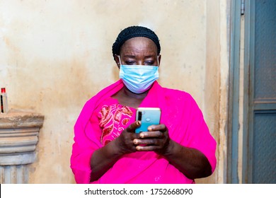 Elderly Black African Senior Woman Wearing Face Mask Using Her Mobile Phone Checking And Researching About Corona Virus