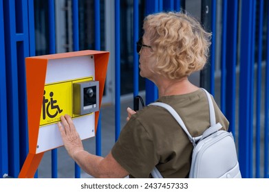 An elderly blind woman reading a text in braille. Button for calling help for people with disabilities.  - Powered by Shutterstock