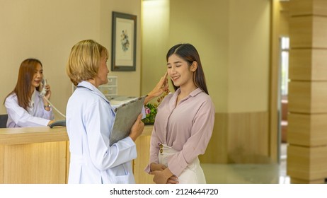 Elderly Blonde Hair Surgical Doctor Discusses With Her Patient For A Cosmetic Or Beauty Treatment Program At Reception Desk. Female Girl Gets Suggestion From A Female Doctor In A Beauty Clinic