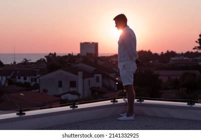 an elderly businessman in casual clothes enjoys the roof of his house at sunset time. Selective focus 