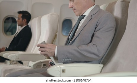 Elderly businessman passenger fasten seatbelt at seat on airplane during flight travelling, Old man wearing a seat belt on the plane before airplane taking off for safe flight