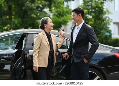 An Elderly Businesswoman Greets Her Personal Driver Or Assistant After Opening The Door For Her.