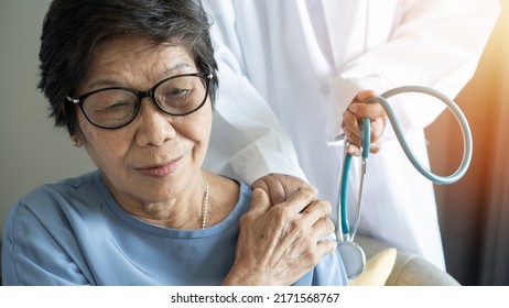 Elderly Care With Asian Old Adult Senior Citizen Patient  Holding Geriatric Doctor, Cargiving Nurse Or Family Assistant's Hand In Hospice Home For Medical Or Mental Therapy