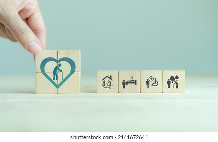 Elderly Care Concept. Hand Holds Wooden Cubes With Icons Related To Elderly Care, Medical, Rehabilitation Service, Nursing Care For Enhancing Quality Of Life In Elder Age. Used For Banner, Background