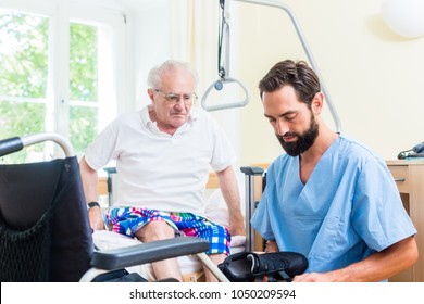 Elderly Care Nurse Helping Senior From Bed To Wheel Chair In Hospital Or Nursing Home