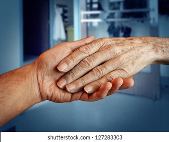 Elderly Care And Senior Health Services With The Hand Of A Young Person Holding And Helping An Old And Aging Patient For In Home Medical Help Due To Aging And Memory Loss In A Hospital Background.