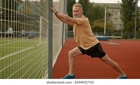 Elderly Caucasian man pensioner athlete outside city stadium physical activity sport flexibility exercise sportsman fitness strong cardio strength recreation energy gymnastic healthy lifestyle aerobic - Powered by Shutterstock