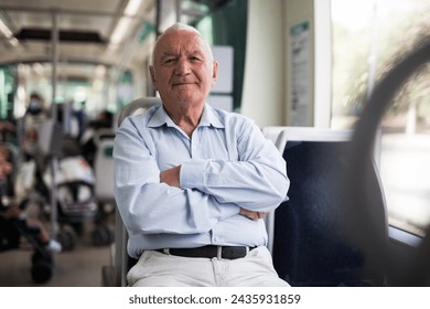 Elderly Caucasian man sitting in tram and looking in camera.