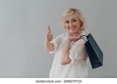 Elderly caucasian old aged woman portrait gray haired portrait with shopping bags on gray background