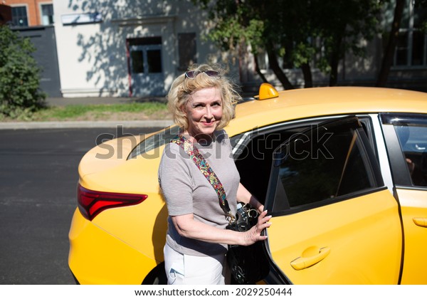 Elderly caucasian old aged woman take taxi car ride\
and opens vehicle door
