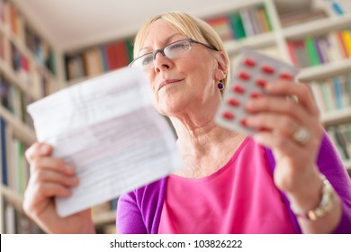 Elderly caucasian woman with medicine and reading drug prescription. Low angle view - Powered by Shutterstock