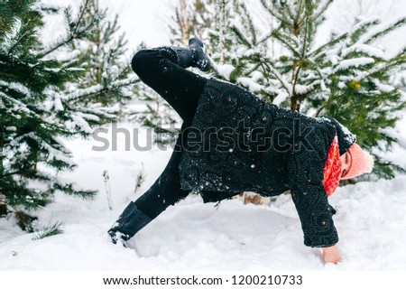 Elderly cheerful woman joking and fooling like child. Happy retiree odd female have fun in winter with face covered in snow. Portrait of adult lady falling in snowdrift at nature.  Childhood memories