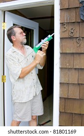 Elderly Contractor Caulking Around Glass Door Frame, Sealing From Possible Air Leaks, Conserving Energy