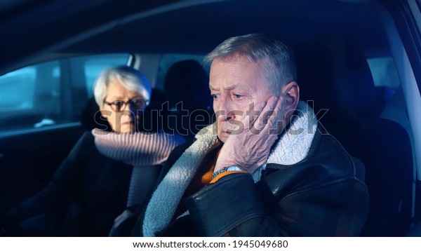 Elderly couple in the car confused with flashing\
police lights. Speeding ticket. Man and woman having argument in\
the car. High quality\
photo