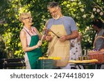 Elderly couple celebrate the 4th of July in their backyard. They are making barbeque, vegetables, and drinking beverages while enjoying and making memories