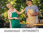 Elderly couple celebrate the 4th of July in their backyard. They are making barbeque, vegetables, and drinking beverages while enjoying and making memories